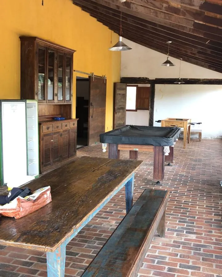 Clínica de reabilitação em Sabará - MG Salão com mesa comprida de madeira, armário antigo e mesa de sinuca