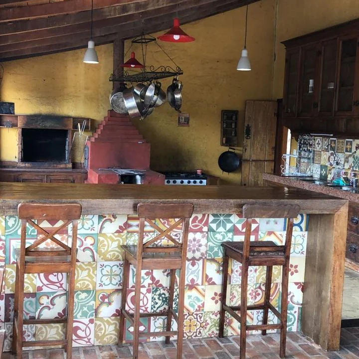 Internação em Sabará - MG Cozinha com balcão de azulejos coloridos, banquetas e panelas penduradas